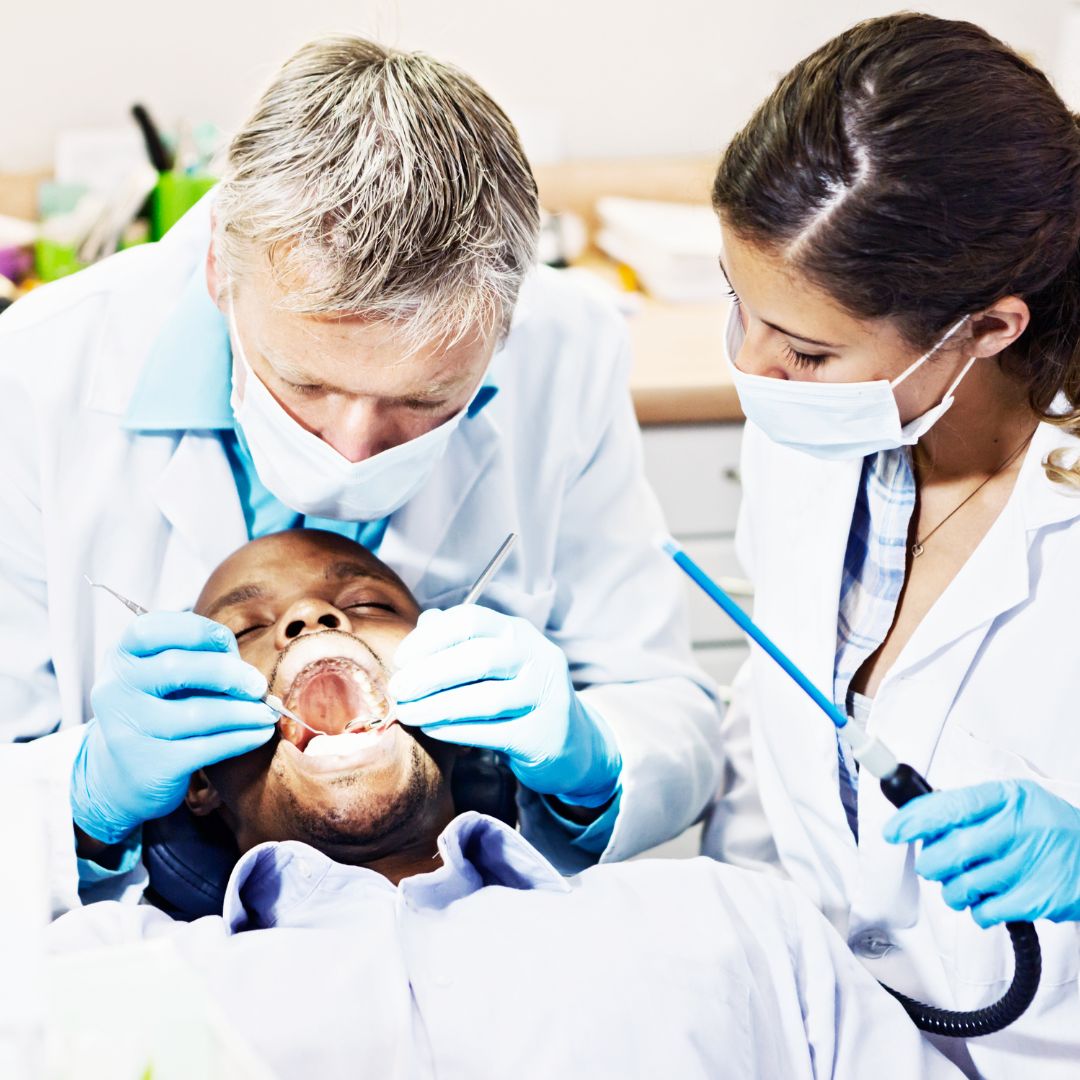 A dentist and a dental assistant working on a patient.